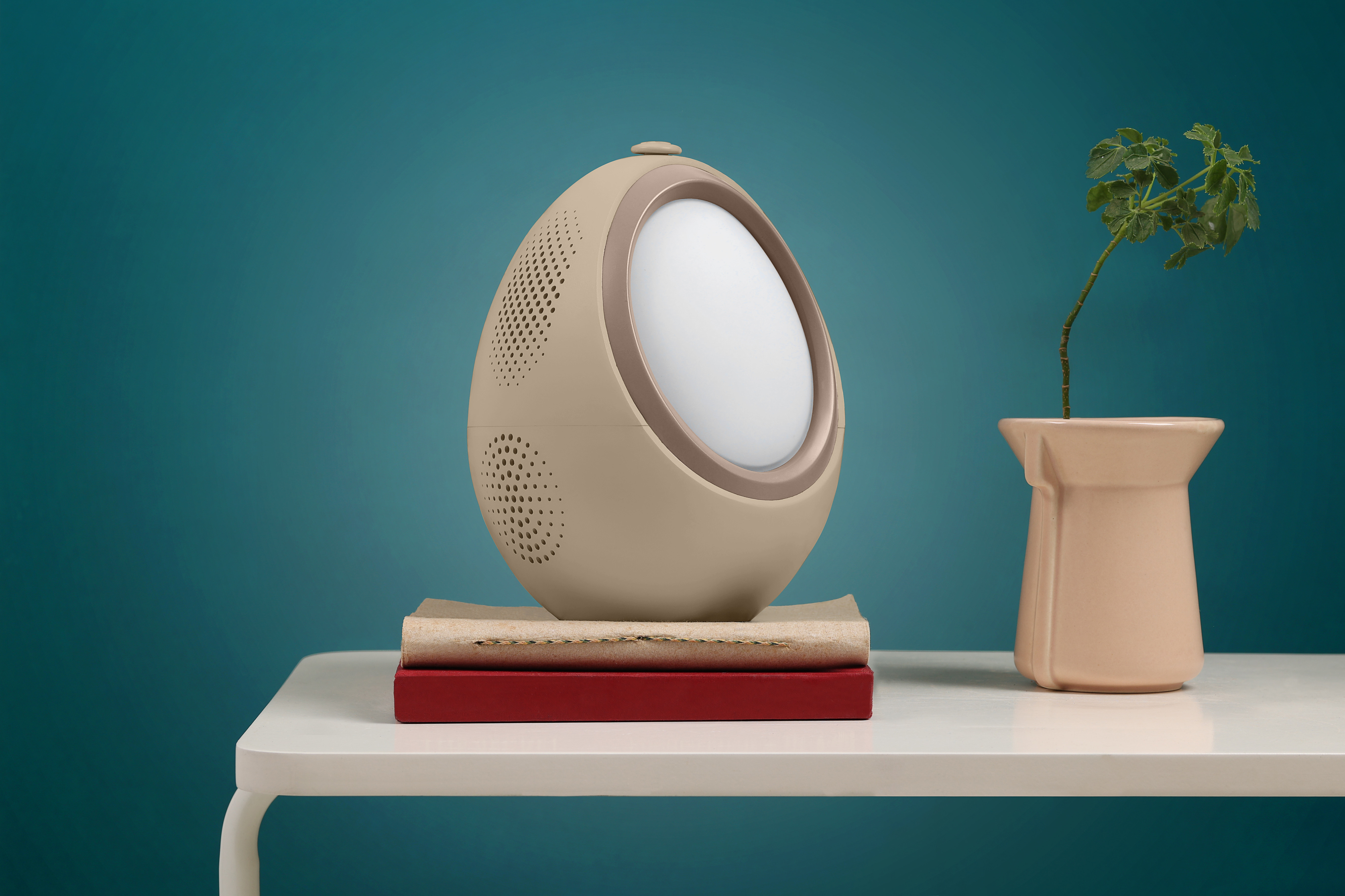 The Naptick device on a side table beside a small plant, against a teal wall